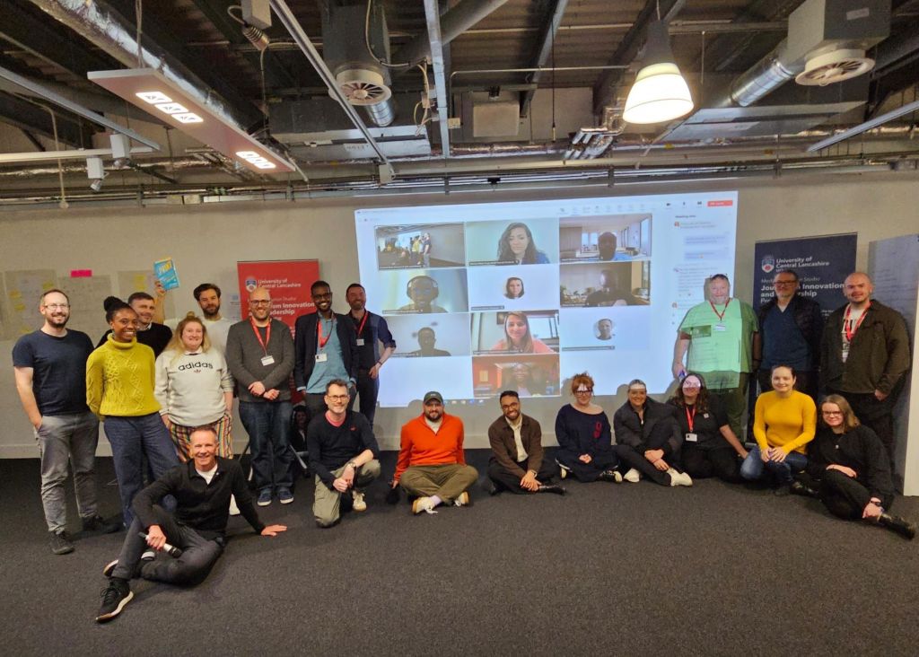 A group of about 15 people are standing and sitting, smiling at the camera. Ed Walker is far left.