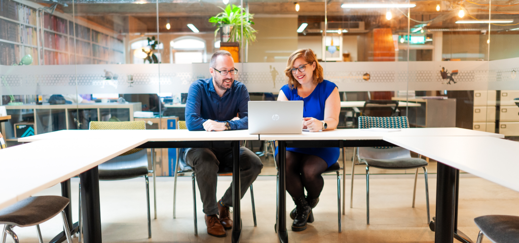 Shirah and Ed are sitting at a table, looking at a laptop